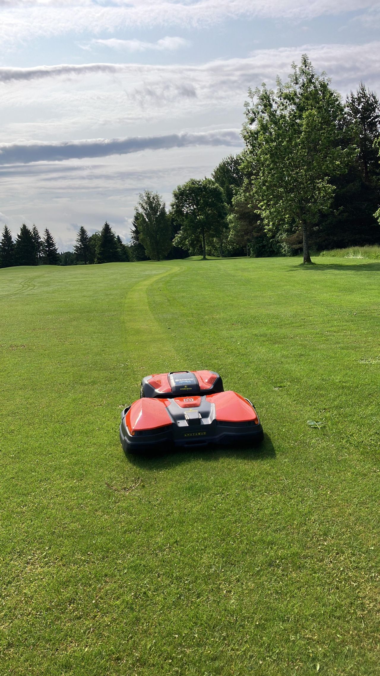 Professional robotic mowers creating perfect stripe patterns on golf course